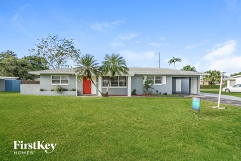 a house with a lawn and palm trees in front of it