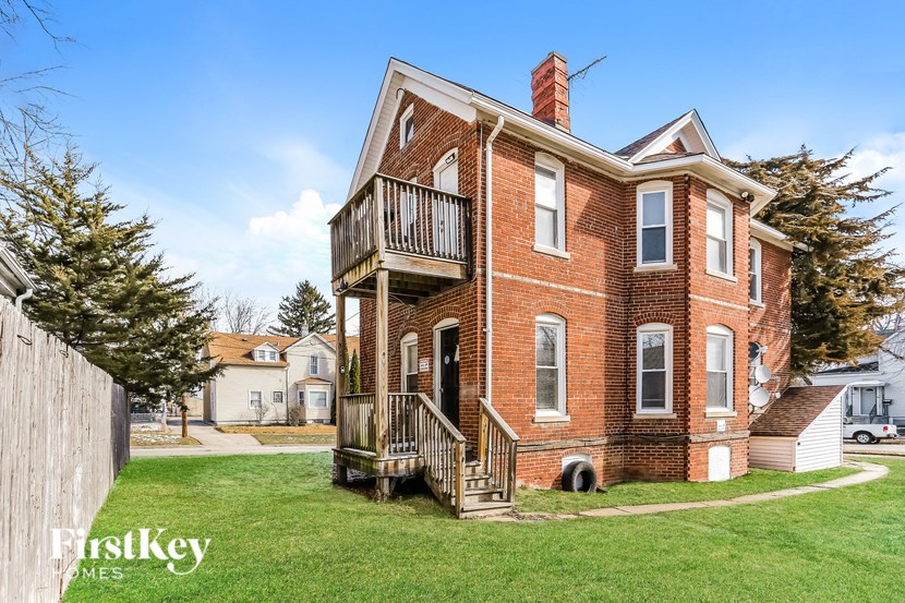 A red brick house with a balcony on the second floor.