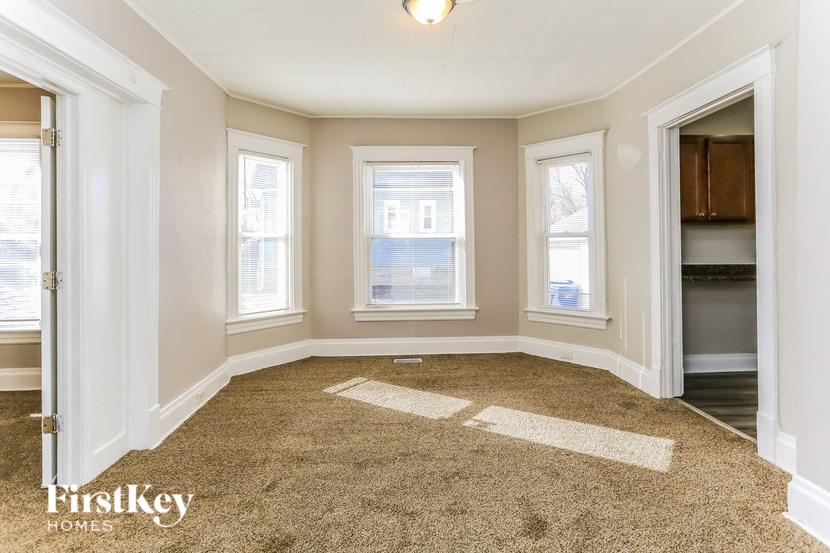 A room with a carpeted floor and two windows.