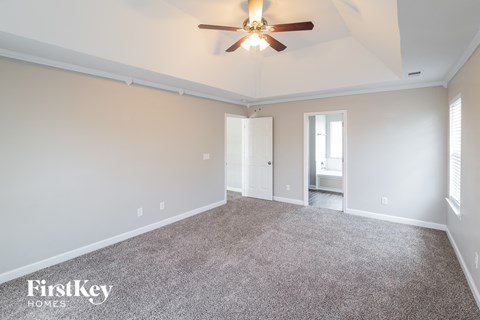 the spacious living room with ceiling fan and carpet