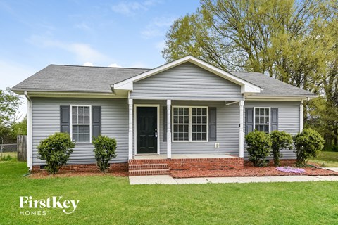 A grey house with a black door and windows is for sale by FirstKey Homes.