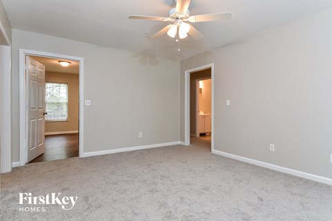 A spacious room with a ceiling fan and two doors.