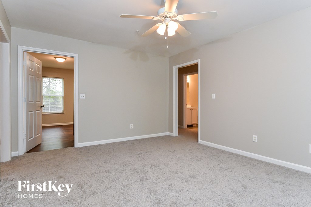 A spacious room with a ceiling fan and two doors.