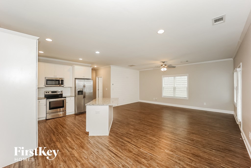 a kitchen and living room with wood floors and white cabinets