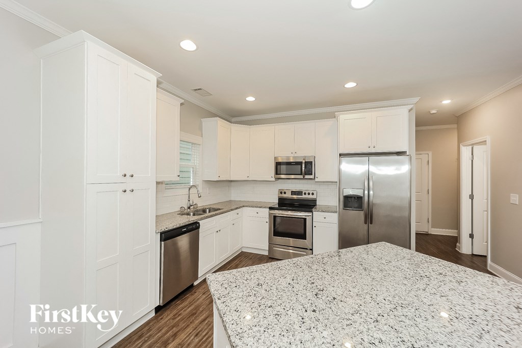 a white kitchen with white cabinets and stainless steel appliances