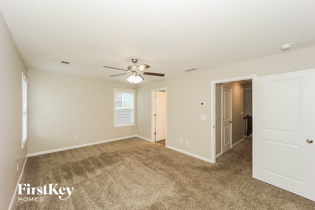 a spacious living room with carpet and a ceiling fan