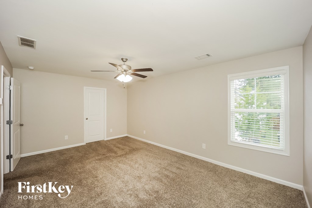 a spacious living room with carpet and a ceiling fan