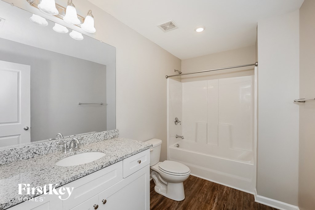a bathroom with a toilet sink and shower and a mirror