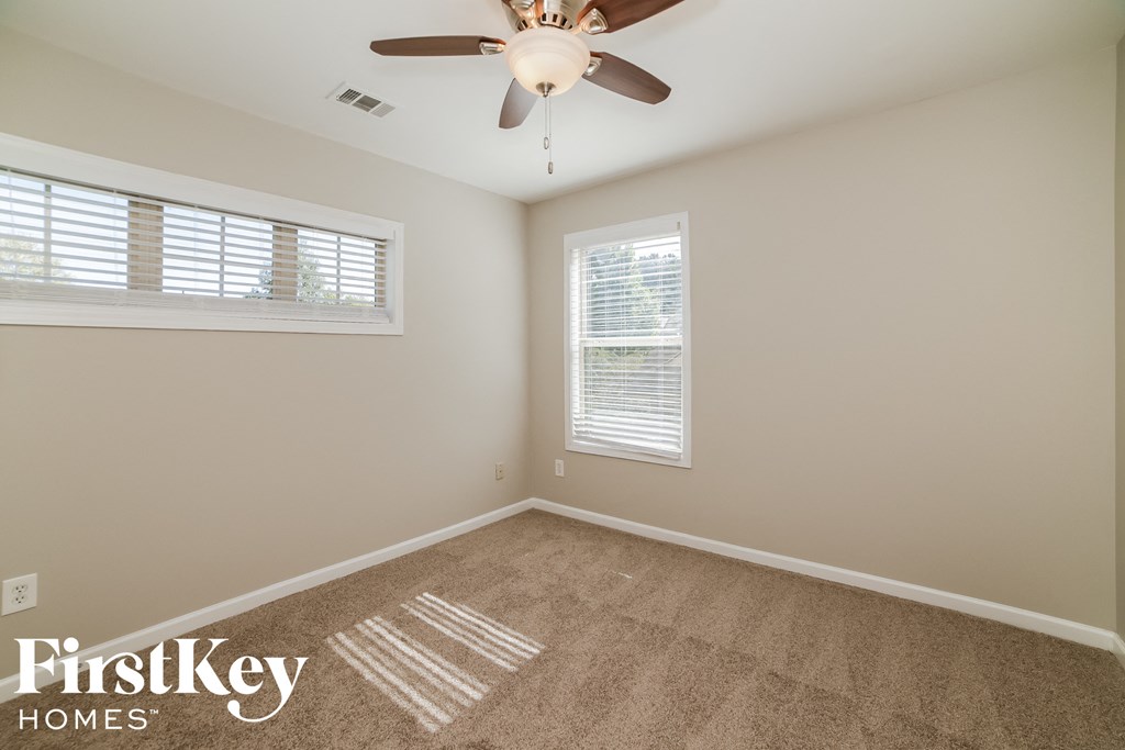 an empty room with a ceiling fan and two windows