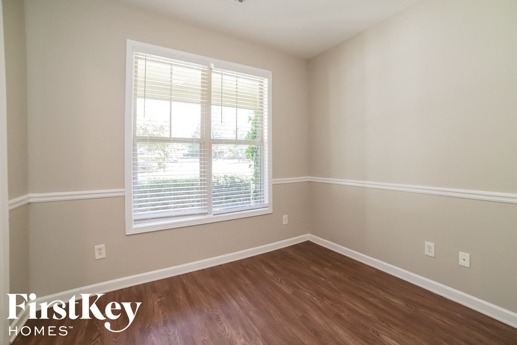 a bedroom with wood flooring and a window