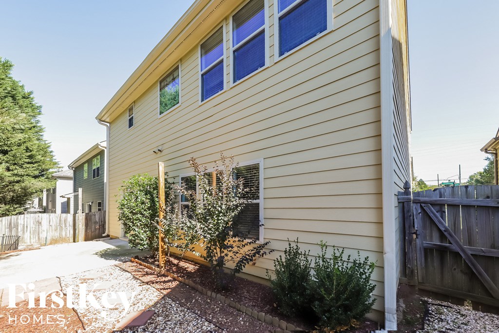 a side view of a house with blue windows and a sidewalk