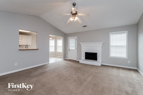 the spacious living room with fireplace and ceiling fan