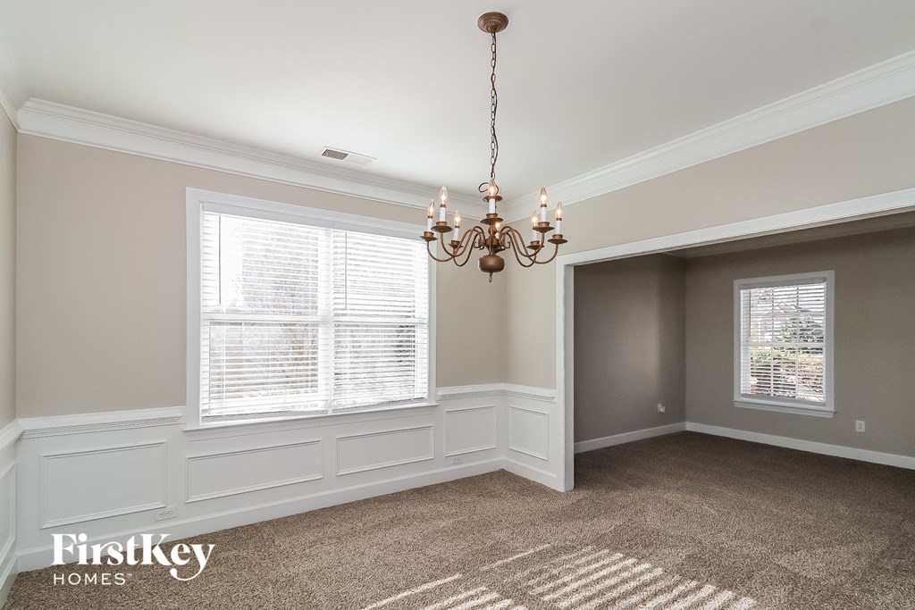 a dining room with a chandelier and two windows