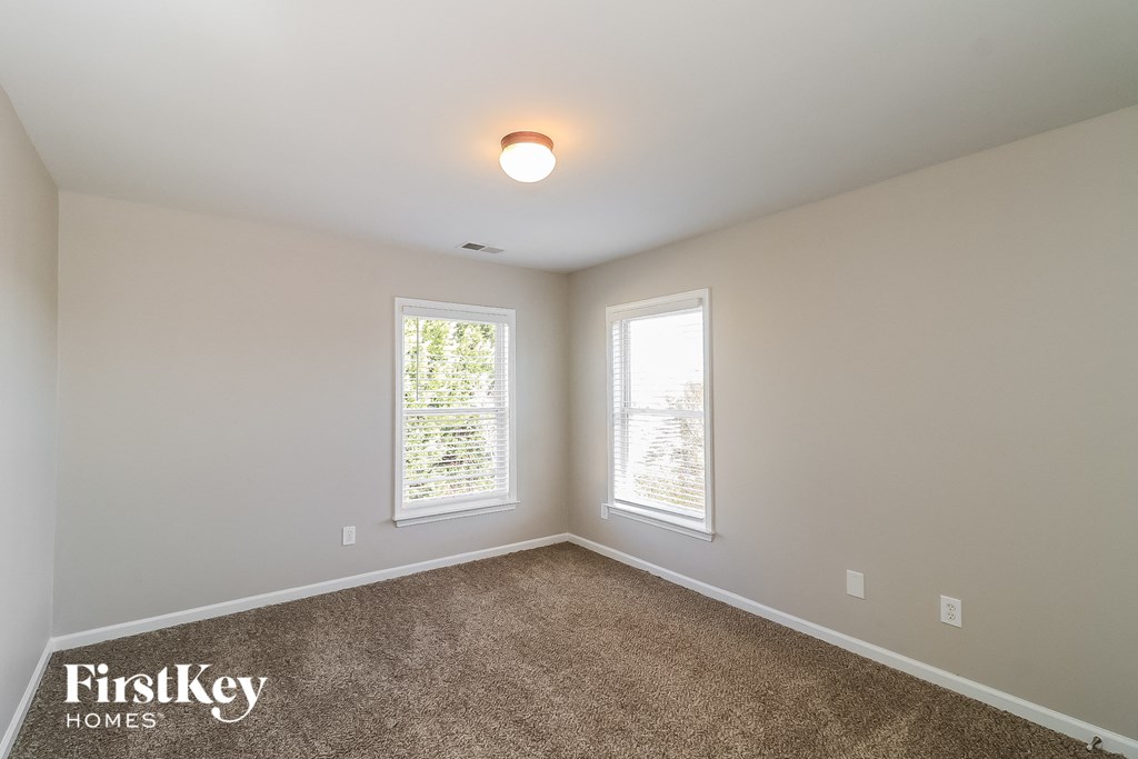 a bedroom with two windows and a carpeted floor