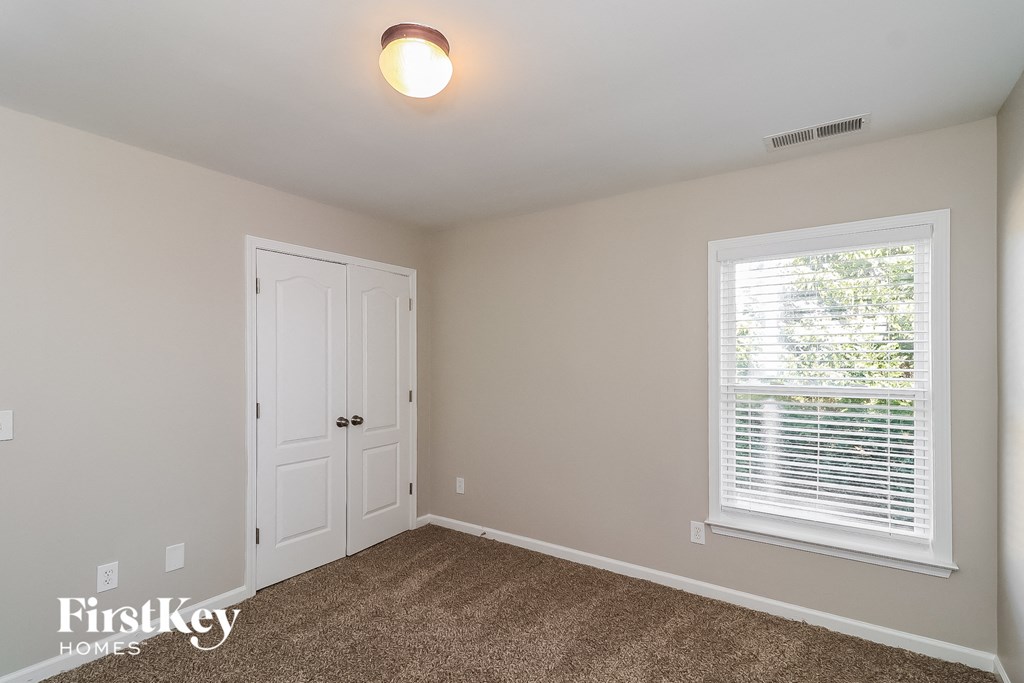 a bedroom with carpet and a door and a window