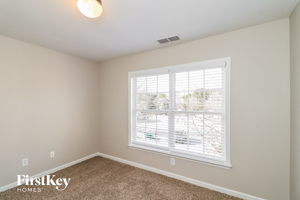 the master bedroom has a large window and carpeted flooring