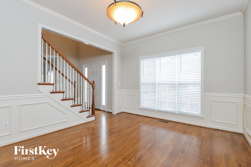 an empty living room with a staircase and a large window