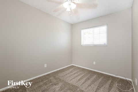 the living room of a home with carpet and a ceiling fan