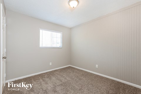 the bedroom of a home with carpet and a window