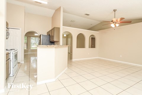 A spacious kitchen and living room with a fan on the ceiling.