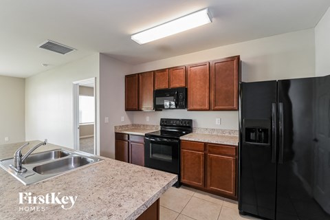 A kitchen with a black refrigerator and brown cabinets.