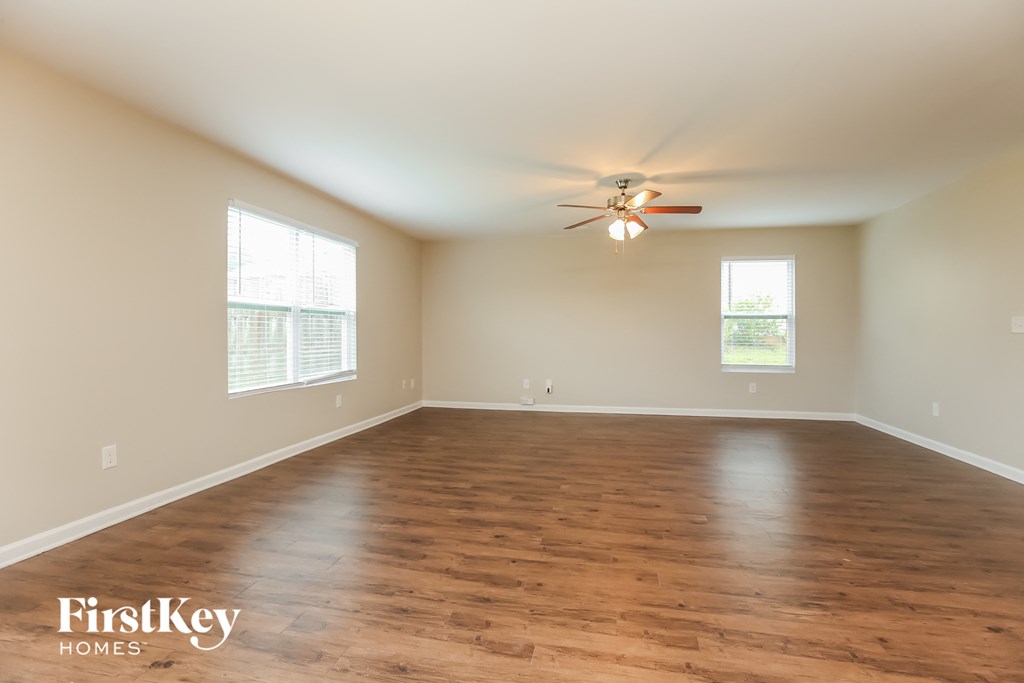an empty living room with wood floors and a ceiling fan