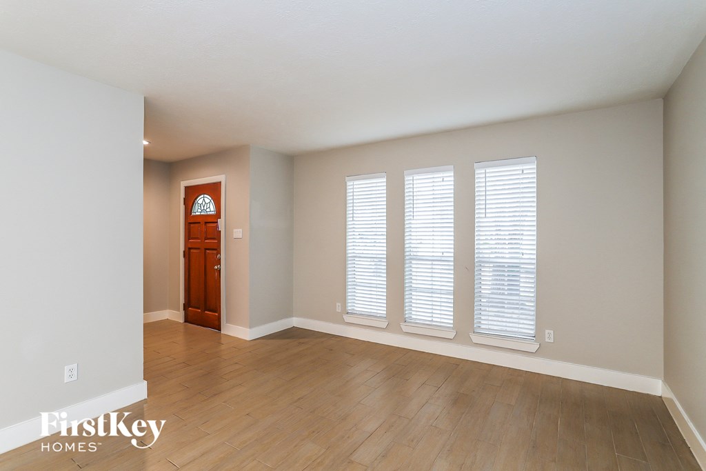 an empty living room with wooden floors and white walls and a wooden door