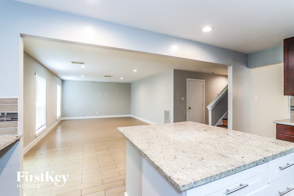 an empty kitchen and living room with a marble counter top