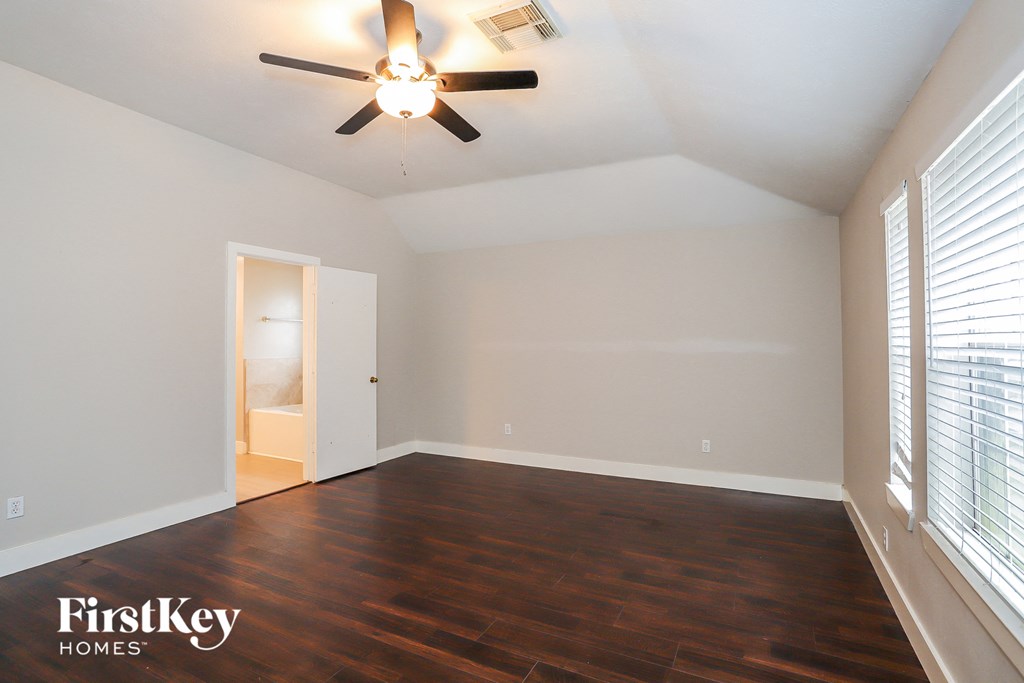 an empty room with a ceiling fan and a door to the bathroom