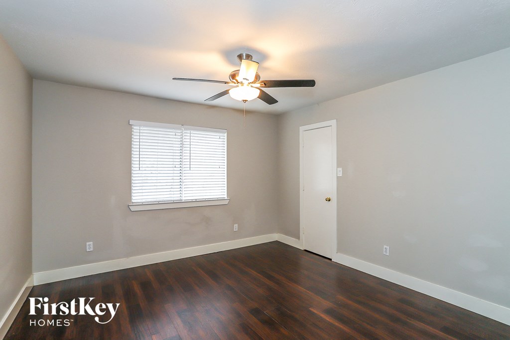 a bedroom with wood floors and a ceiling fan