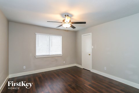 a bedroom with wood floors and a ceiling fan