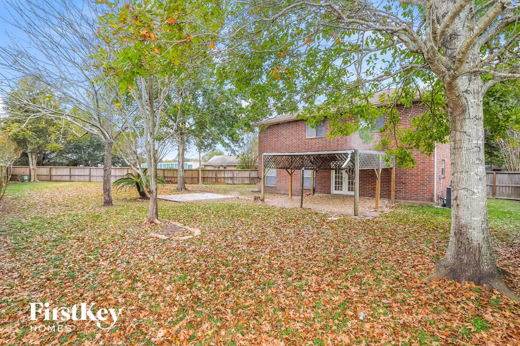a backyard with trees and a brick house with a fence