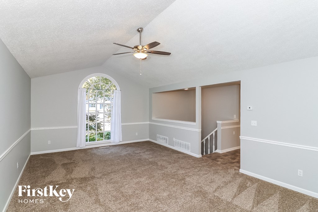 an empty living room with a ceiling fan and a window