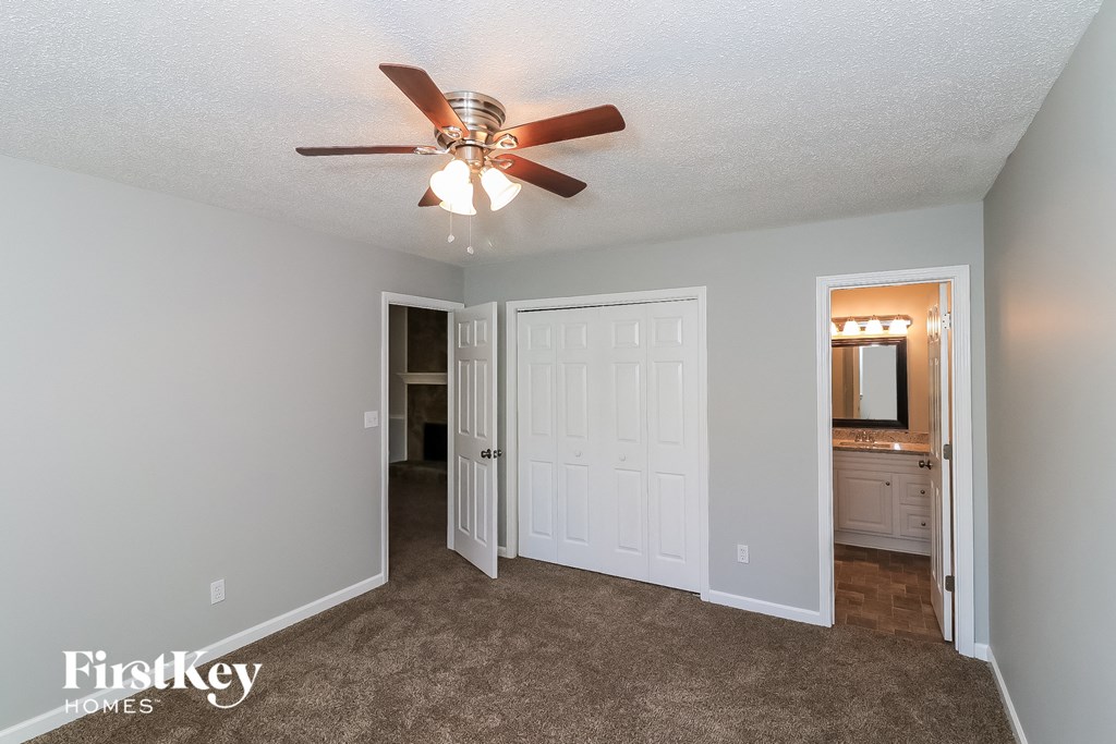 a living room with a ceiling fan and a door to a bathroom