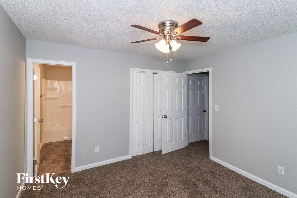a bedroom with a ceiling fan and a door to a closet