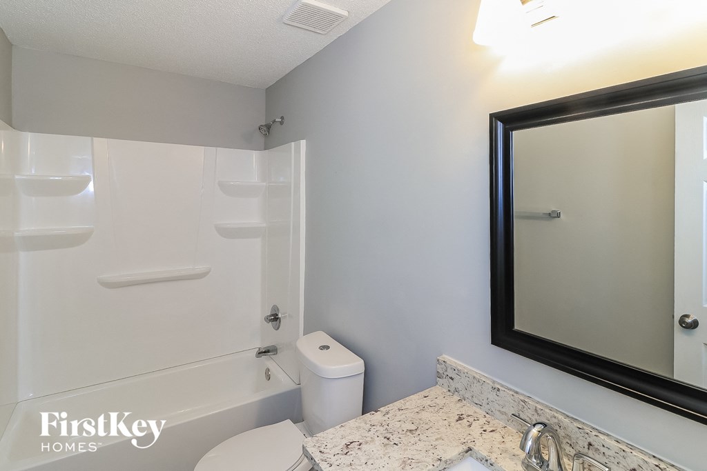 a bathroom with a mirror and a toilet and a bath tub