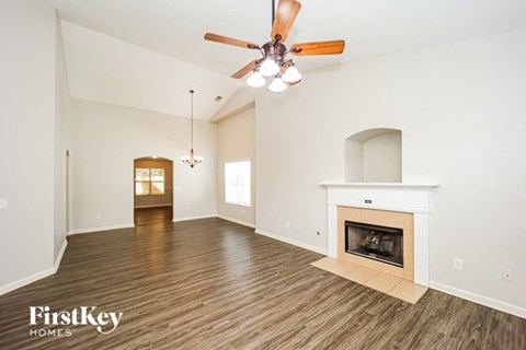 A spacious living room with a fireplace and a ceiling fan.