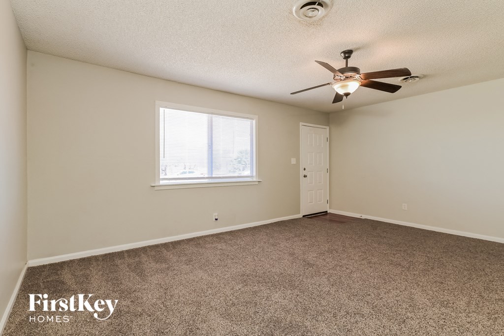A room with a carpeted floor and a ceiling fan.