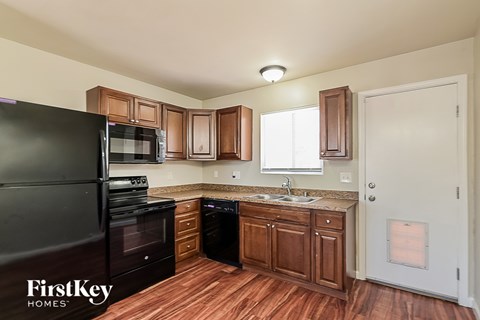 A kitchen with wooden cabinets and a black refrigerator.