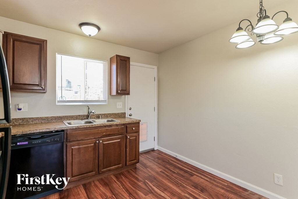 A kitchen with wooden cabinets and a black dishwasher.