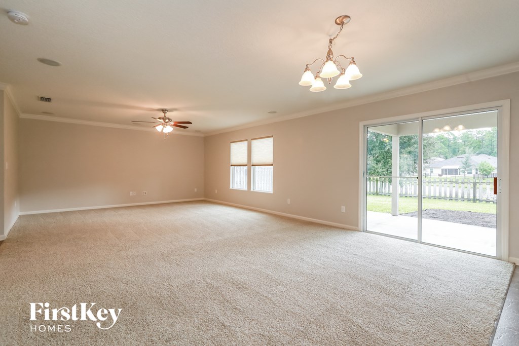 an empty living room with a ceiling fan and a sliding glass door