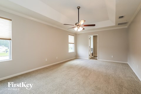 the spacious living room with ceiling fan and carpeting