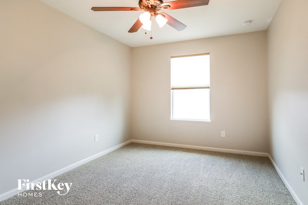 an empty room with a ceiling fan and a window