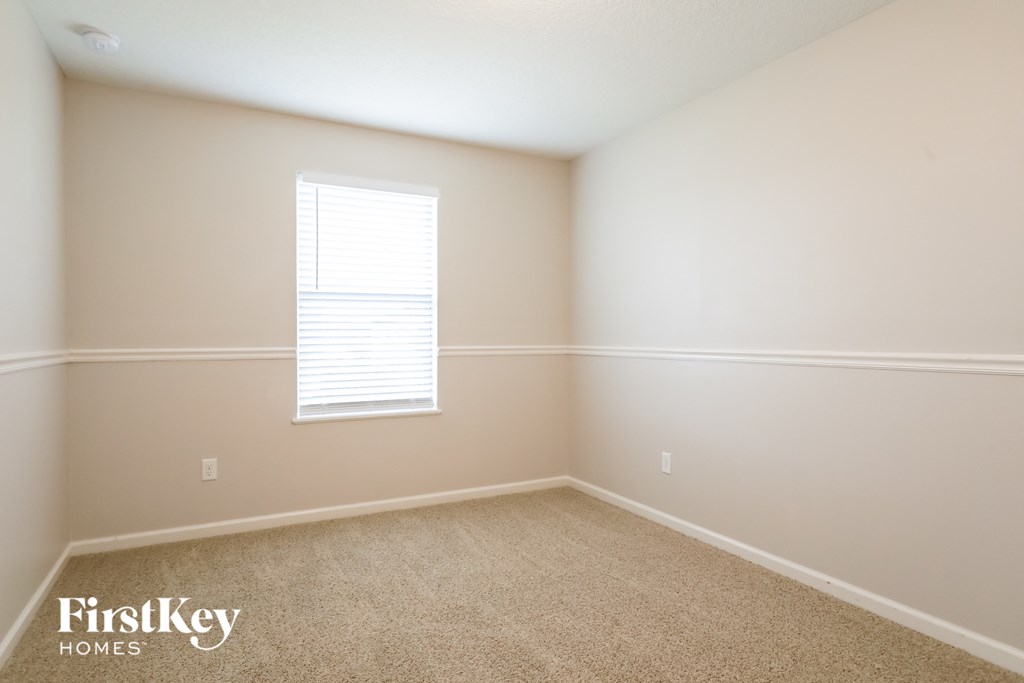 a large empty room with a window and beige carpet