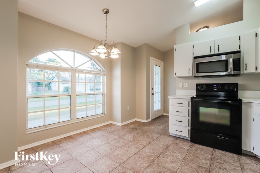A kitchen with a black oven and white cabinets.