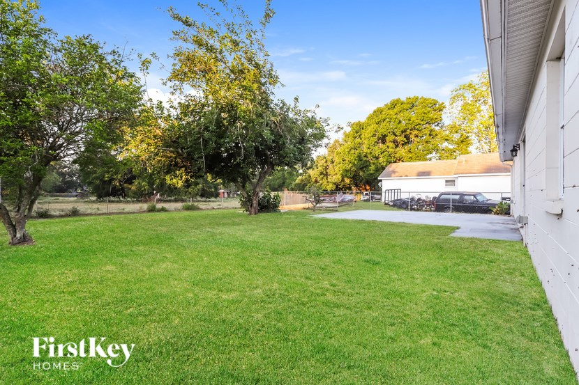 A white house with a lawn and trees in the background.