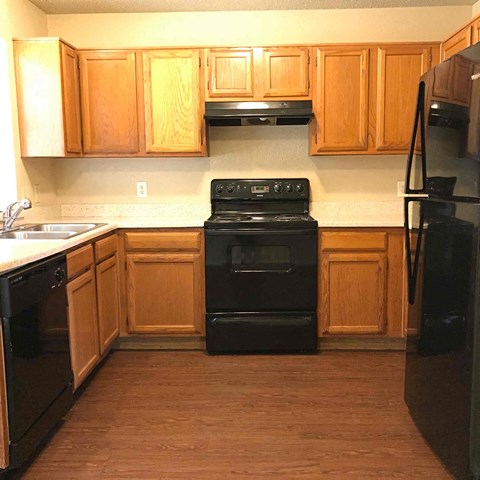 A kitchen with wooden cabinets and black appliances.