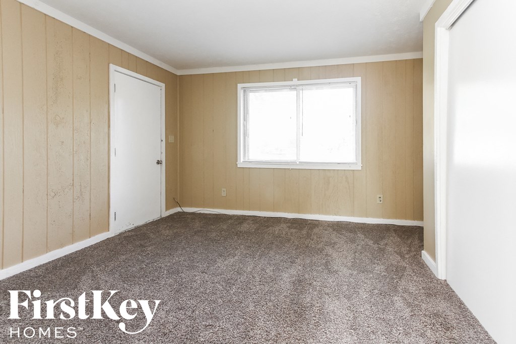 A room with a carpeted floor, a window, and a door.