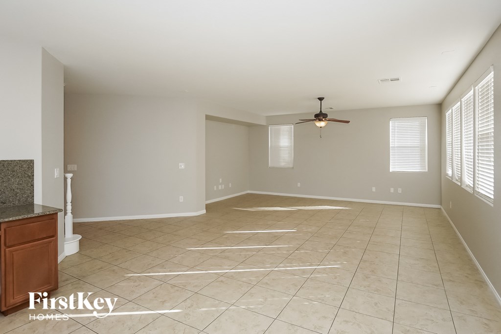 an empty living room with tiled floors and a ceiling fan