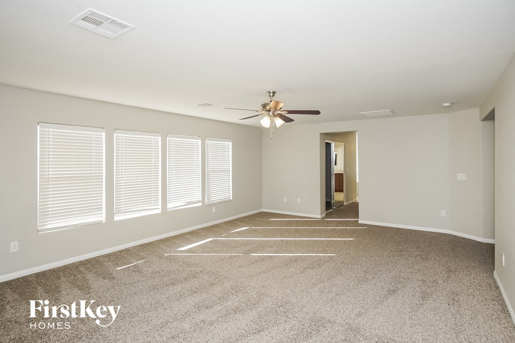 an empty living room with a ceiling fan and windows